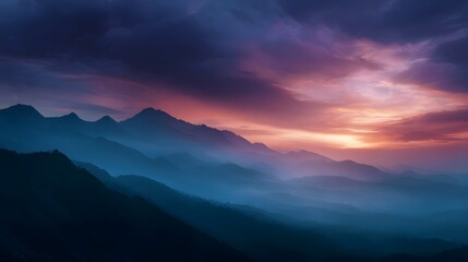 Obraz premium Majestic mountain range illuminated by a vibrant sunrise with layers of mist creating depth and atmospheric haze