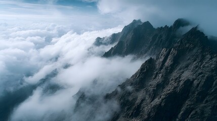 Aerial view of rugged mountain peaks shrouded in dramatic clouds