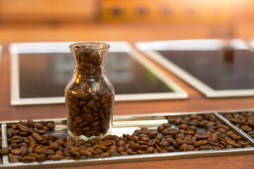 Workers prepare samples of arabica and robusta coffee beans using roasting machines and a tasting setup in a workshop filled with roasting aromas