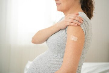 Expecting mother arm with fresh vaccination bandage. Important step in scheduled prenatal...