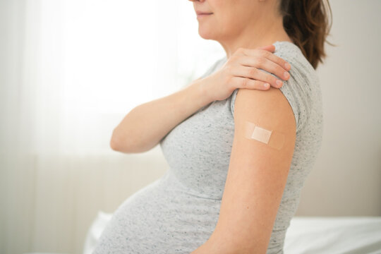 Expecting mother arm with fresh vaccination bandage. Important step in scheduled prenatal immunization program.