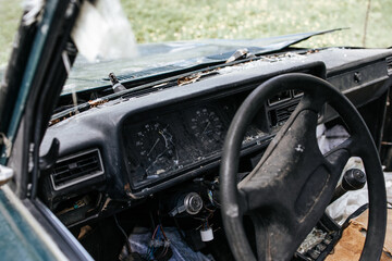 Fototapeta premium Car after an accident. Abandoned old car on the side of the road. The dashboard and steering wheel of a car. Broken windshield.