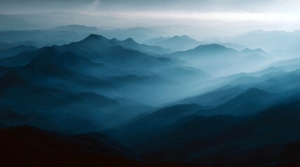 Obraz premium Vast layered blue mountain ranges receding into atmospheric haze under a soft cloudy sky