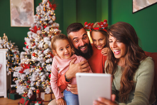 Family having fun taking selfies by the Christmas tree