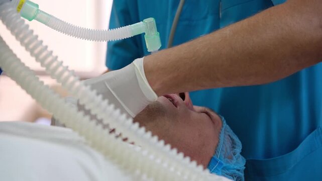 Medical professional carefully inserts endotracheal tube into the throat of a sedated patient lying on an operating table, ensuring proper airway management during a surgical procedure