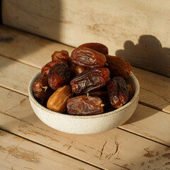 Dried dates in a white bowl on a wooden surface