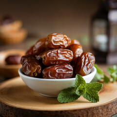 Dried dates in a white bowl on a wooden surface