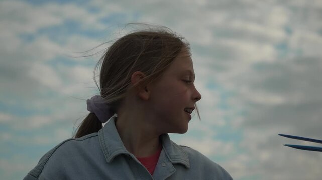 Girl, airplane, sky, launching toy plane with joy under cloudy summer sky