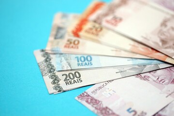 Close up brazilian reais money bills in big amount on blue. Pile of Brazil real currency banknotes