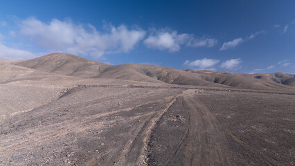 `Desert Track Through Volcanic Hills Under Clear Sky – Remote Arid Landscape
