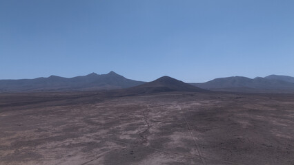 Desert Track Through Volcanic Hills Under Clear Sky &ndash; Remote Arid Landscape