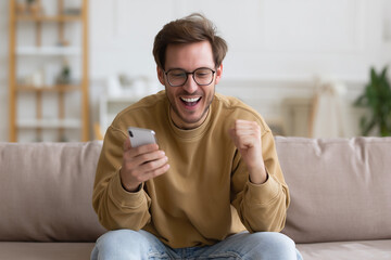 Excitement fills the room as young man celebrates good news while checking his smartphone in a cozy living area Generative AI