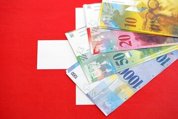 Swiss franc banknotes and flag. The current francs money bills lies on flag in big amount