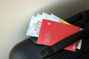 Swiss passport and franc money bills on travel bag. Pass and banknotes on bag close up