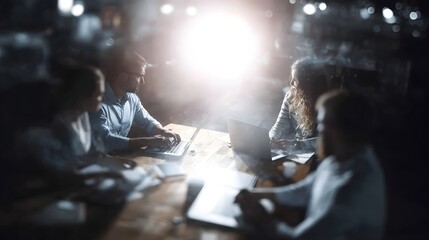 Team working collaboratively around a table with laptops at night