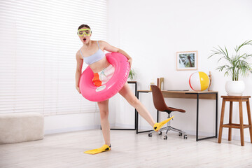 Woman in diving mask and flippers with inflatable ring having fun at home. Dreaming about vacation at sea © New Africa