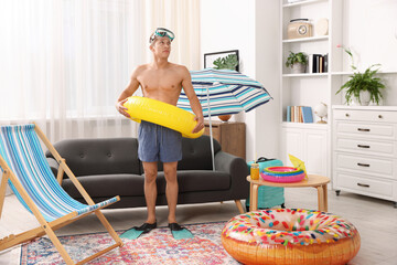 Man in flippers with diving mask and inflatable ring at home. Dreaming about vacation at sea © New Africa