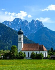 Picturesque church nestled in a valley, with majestic mountains in the background