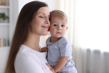 Mother with her cute little baby at home, space for text
