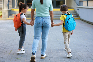 Obraz premium Mother taking her children to school outdoors, back view