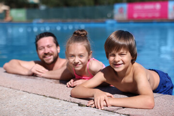 Happy father and his kids resting in swimming pool outdoors. Family vacation