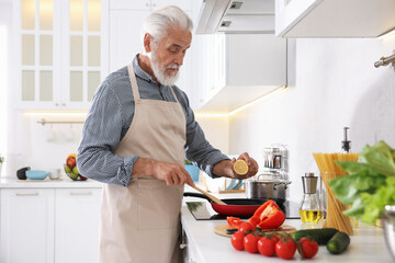 Elderly man cooking dish on cooktop in kitchen