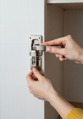 Hands adjusting cabinet lock in minimalistic kitchen, home improvement
