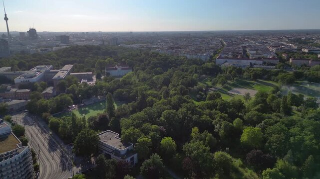 Sez and Volkspark Friedrichshain in Berlin, showcasing its lush greenery, a passing tram on a sunny day. speed ramp hyper motion time lapse Great aerial view flight overflight flyover drone