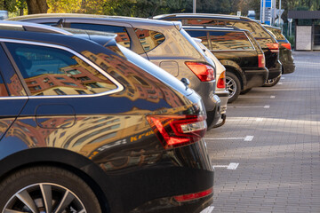 Fototapeta premium Several vehicles stand neatly lined up in a well-organized parking area with morning sunlight creating reflections on their surfaces