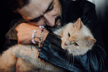 Obraz premium young man with cat. portrait of a handsome man with dark hair and a black beard