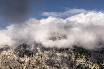 mountain peak covered by lush clouds on clear blue sky backdrop. minimalist background with close up view of mountain range