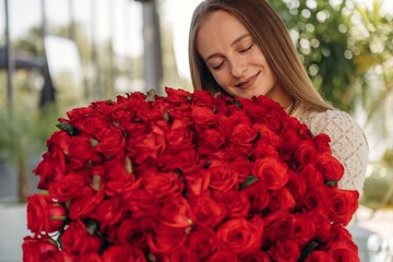 Happy young woman is with big bouquet of roses