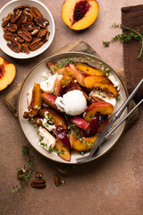 Fresh gourmet salad with burrata cheese, caramelized peaches, pecan nuts, thyme, and honey dressing on wooden table.