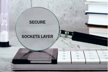 A magnifying glass reveals the phrase secure sockets layer on a calculator while books are stacked in the background, highlighting the importance of online security