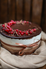 Layered chocolate mousse cake decorated with red berries and ribbon