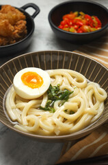 Kake udon with egg. Japanese traditional noodle. served with tempura and sliced chili.