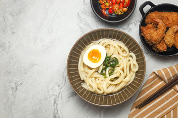 Kake udon with egg. Japanese traditional noodle. served with tempura and sliced chili.