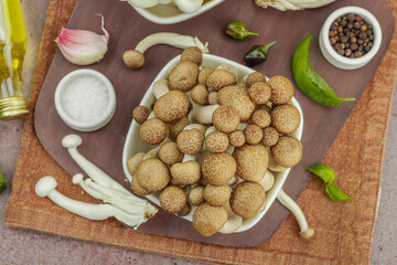 Fresh assorted shimeji mushrooms with olive oil, basil, garlic, salt, pepper on rustic background