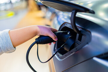A person is holding an electric car charger and charging the electric car battery.