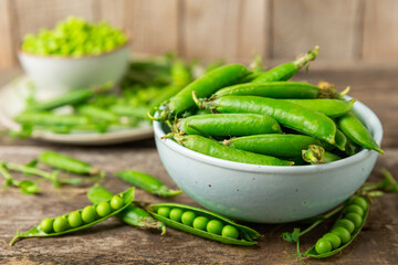 Fresh green pea pods with green peas on a wooden background. Sweet green peas. Green pea beans vegetables. Vegan. healthy vegetable. Copy space