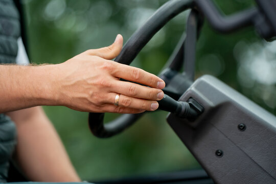 Hand resting on steering wheel of heavy machinery outdoors, representing human work, responsibility, labor, and connection between driver and industrial vehicles in modern construction life