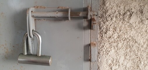 Metal padlock attached to steel door latch, symbolizing industrial security, property protection, access control, and safety in construction, storage, and warehouse environments.