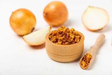 Crispy fried onions in a bowl on a wooden table. Roasted Onions. Seasoning for dishes. Spices. Salad dressing. Space for text. Copy space