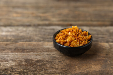 Crispy fried onions in a bowl on a wooden table. Roasted Onions. Seasoning for dishes. Spices. Salad dressing. Space for text. Copy space