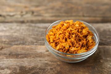 Crispy fried onions in a bowl on a wooden table. Roasted Onions. Seasoning for dishes. Spices. Salad dressing. Space for text. Copy space