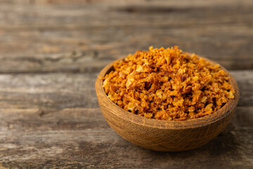 Crispy fried onions in a bowl on a wooden table. Roasted Onions. Seasoning for dishes. Spices. Salad dressing. Space for text. Copy space
