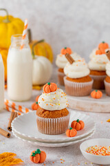 Pumpkin spice cupcakes decorated butter cream frosting, sugar sprinkles and mini sweet pumpkins on top. Thanksgiving or Halloween dessert.