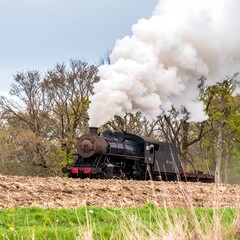 Obraz premium Vintage steam locomotive chugging through countryside