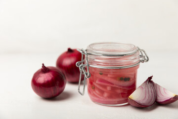 Pickled onions in a glass jar on the table. pickled red onion. Vegetarian spicy dish. Delicious homemade marinated pickled purple onions . Space for text. Copy space.