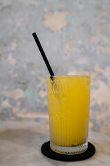 Refreshing glass of orange juice with straw on a light background